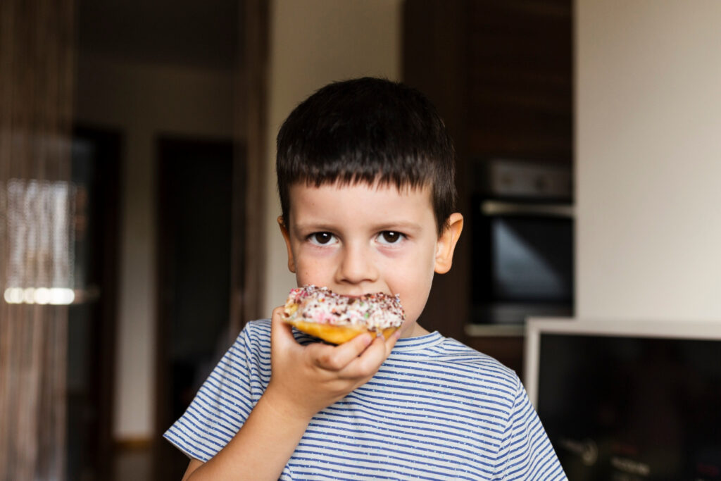 Criança comendo um donut. Obesidade infantil.