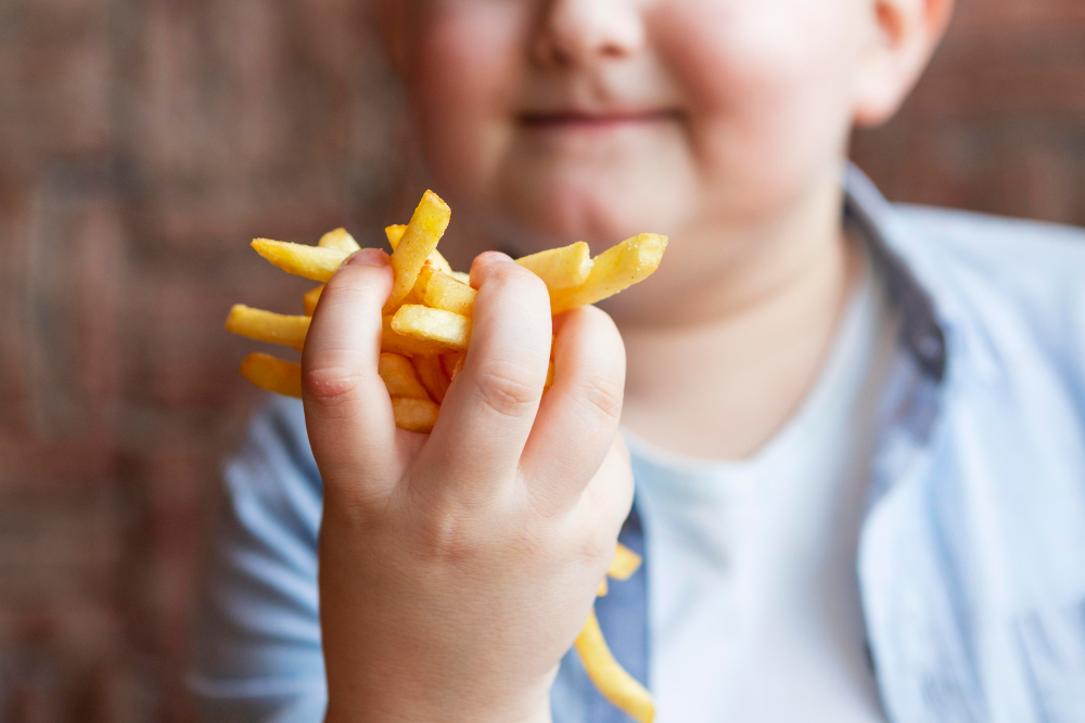 Criança comendo batatas fritas. Obesidade infantil.